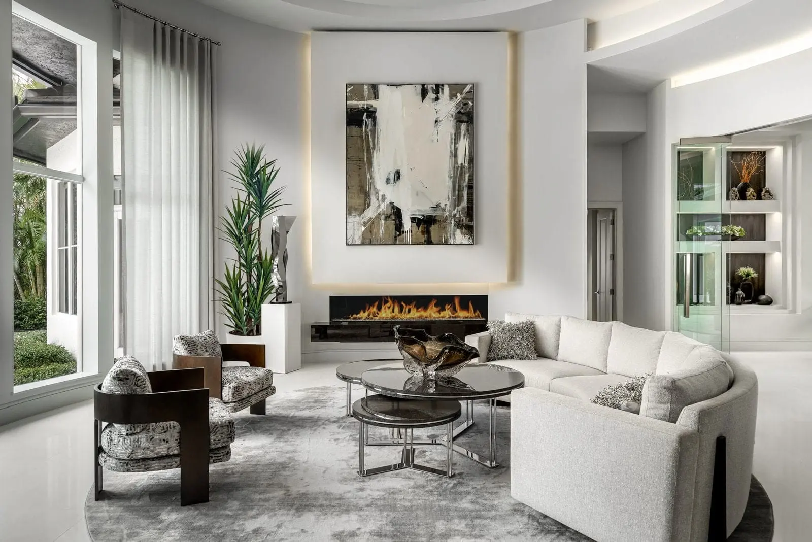 Curved white sectional sofa and modern fireplace in a luxury Palm Beach living room.