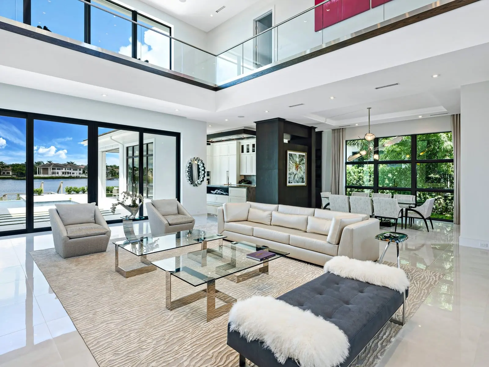 Open-concept waterfront living room with glass walls, modern furnishings, and lake views in a Palm Beach luxury home.