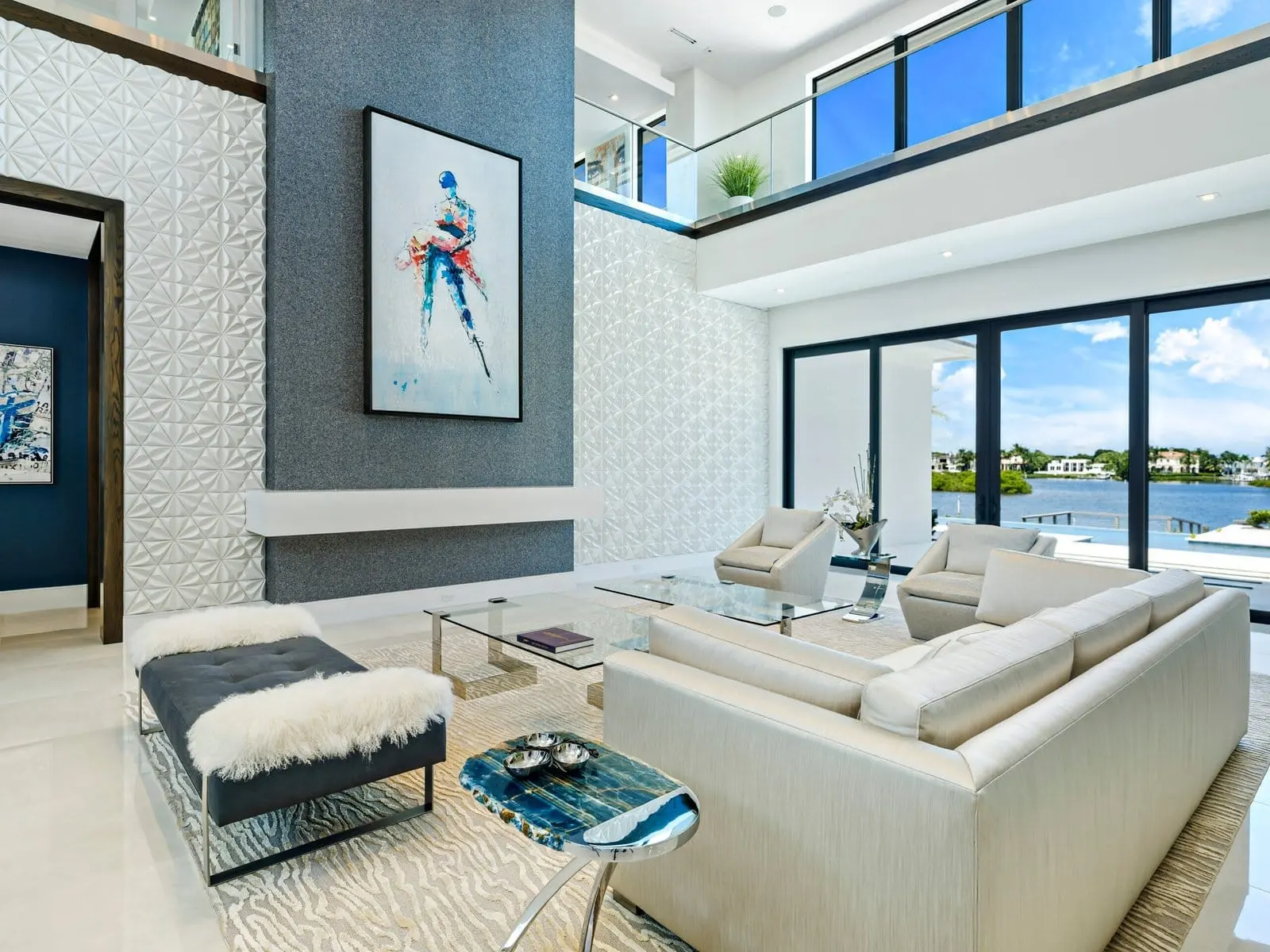 Contemporary Palm Beach living room with double-height ceilings, textured accent wall, and panoramic waterfront views.