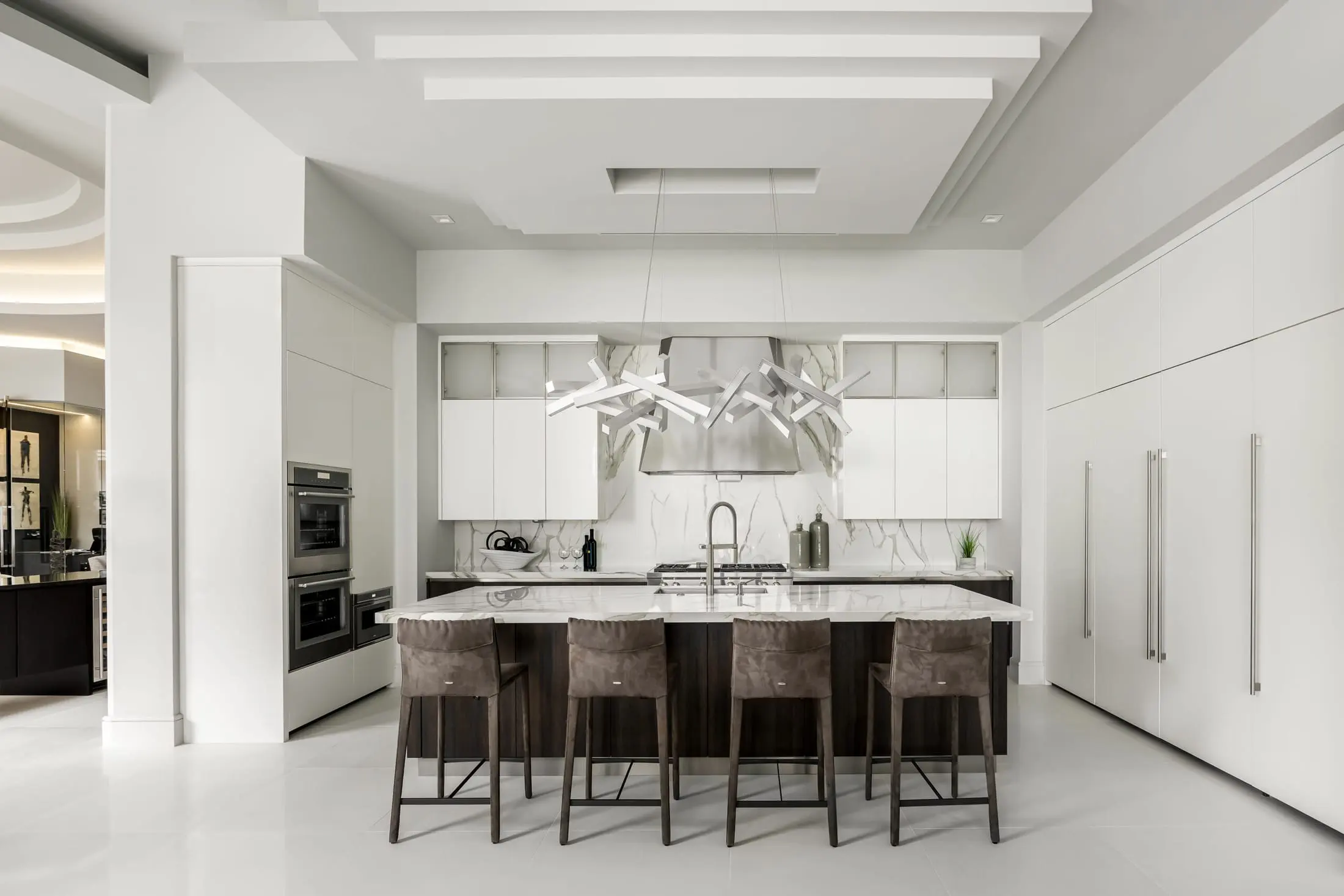 Modern kitchen with marble island, sleek white cabinetry, and sculptural pendant lighting.