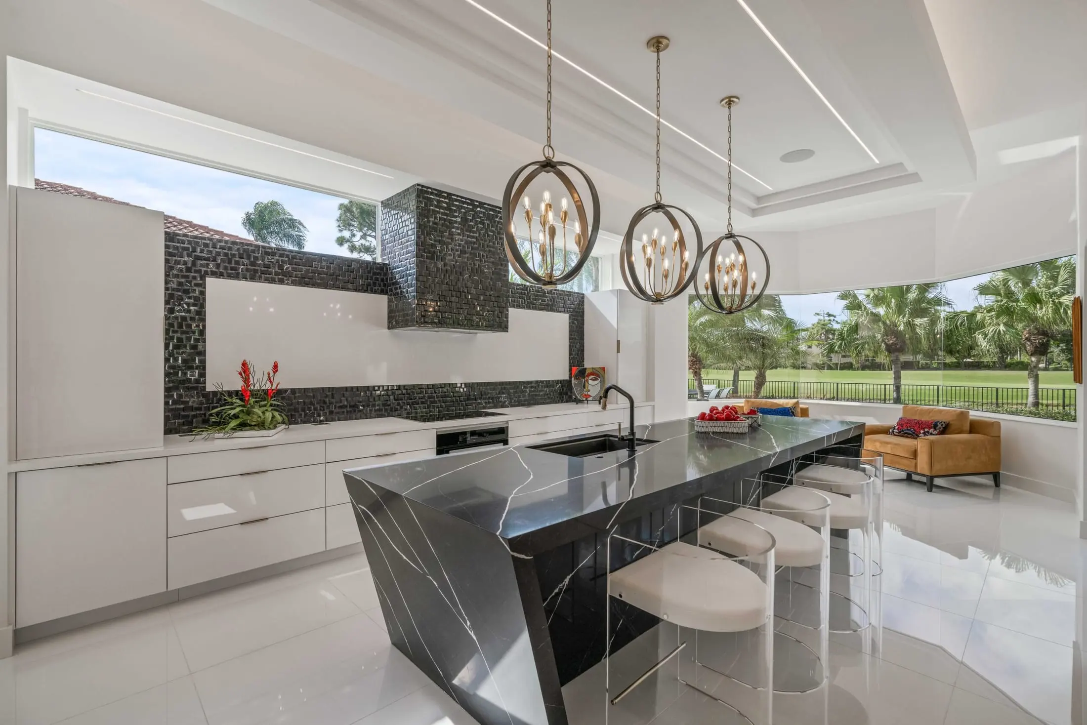 Delray Beach luxury kitchen with a bold black waterfall island, pendant lighting, and floor-to-ceiling windows overlooking palm trees.