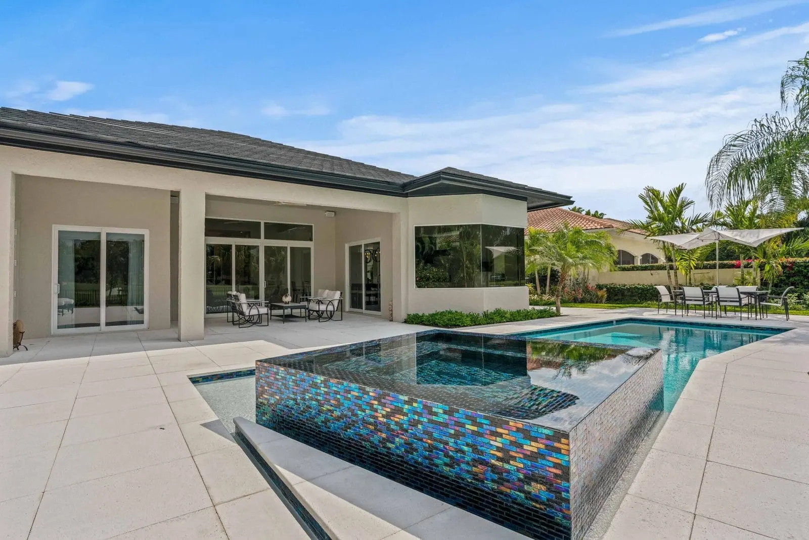 Modern luxury pool and spa with iridescent tile detail in a Delray Beach backyard patio from the Modern Masterpiece project.