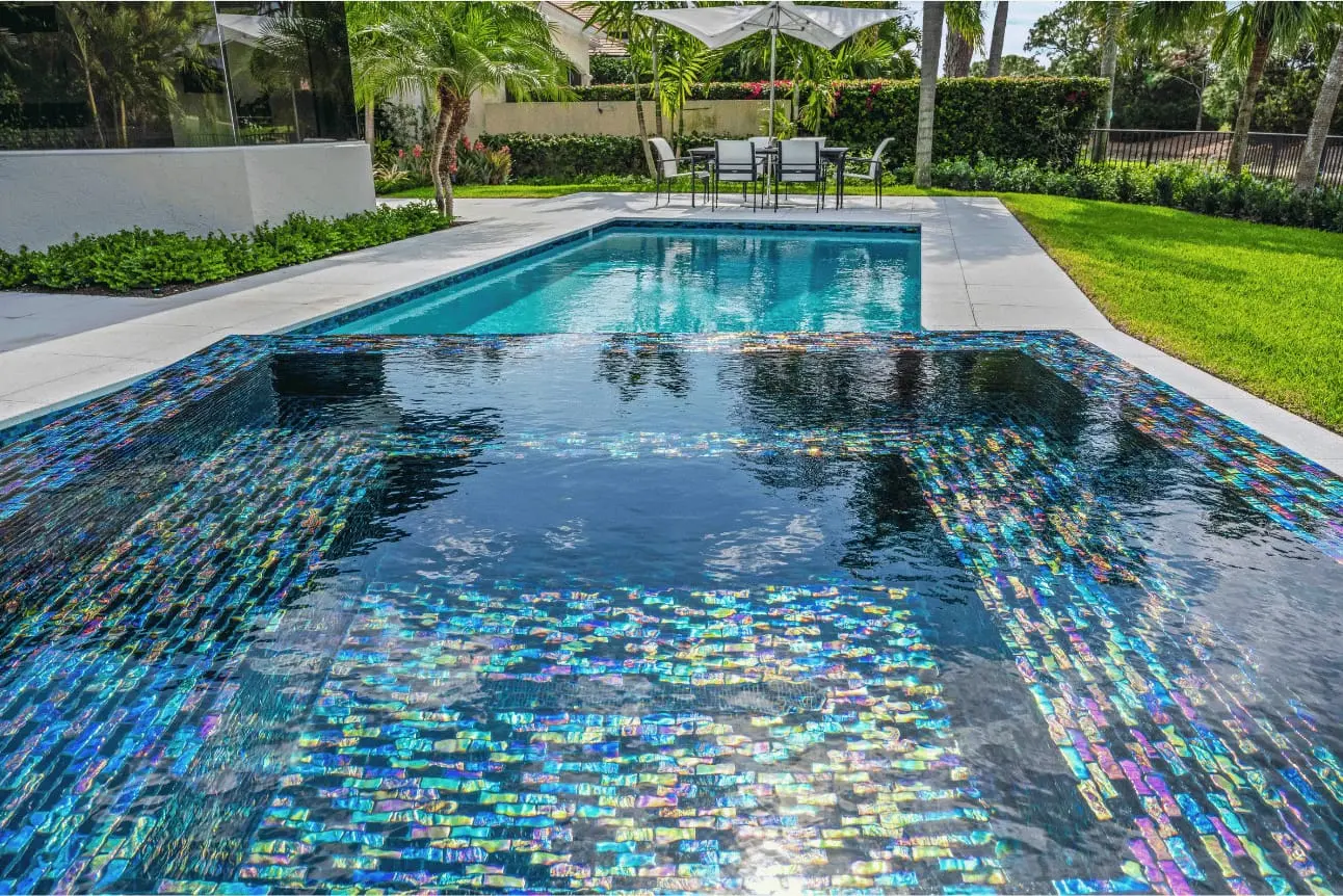 Modern pool with iridescent glass tile and a raised spa in a Delray Beach backyard.