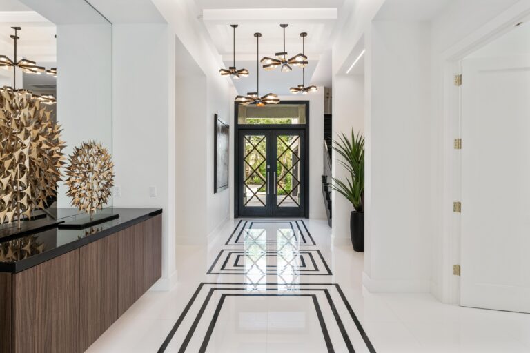 Modern foyer with geometric black-and-white tile floor, gold sculptural decor, and glass double door