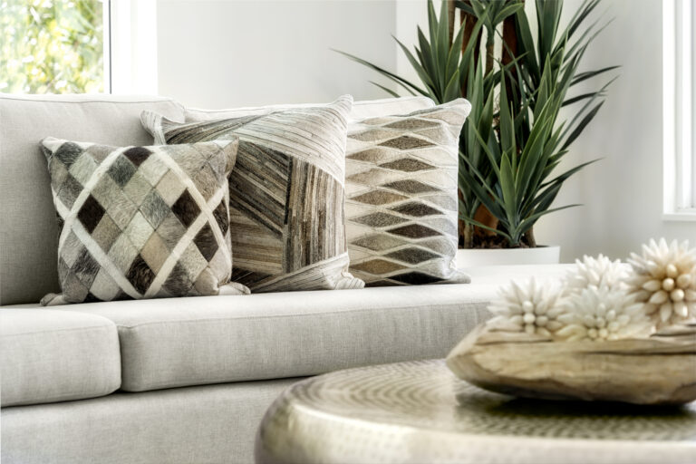 Neutral throw pillows with geometric patterns on a light sofa beside natural decor and greenery.