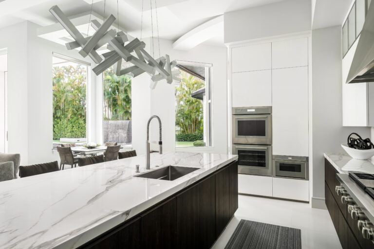 Luxury kitchen with marble countertops, modern pendant lighting, and built-in stainless steel appliances.