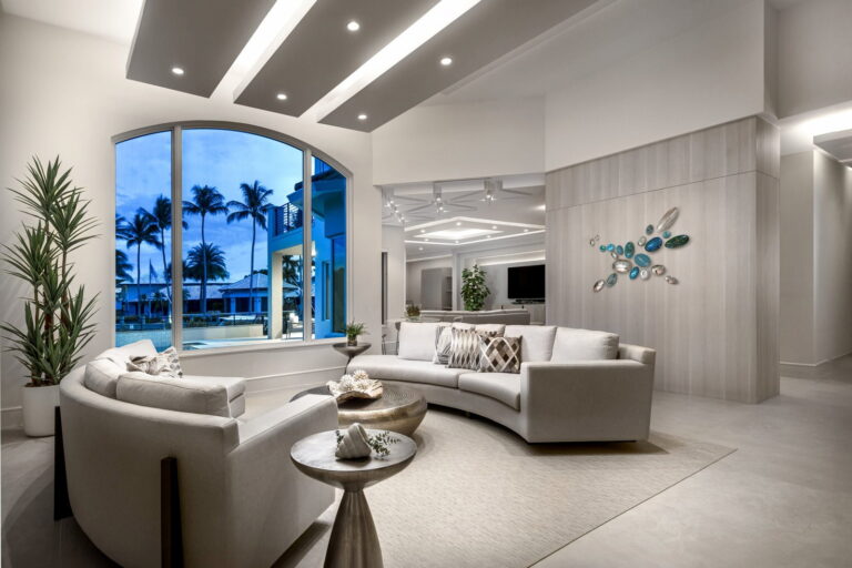 Boca Raton coastal living room at night with modern lighting, arched window, and curved white sectional.