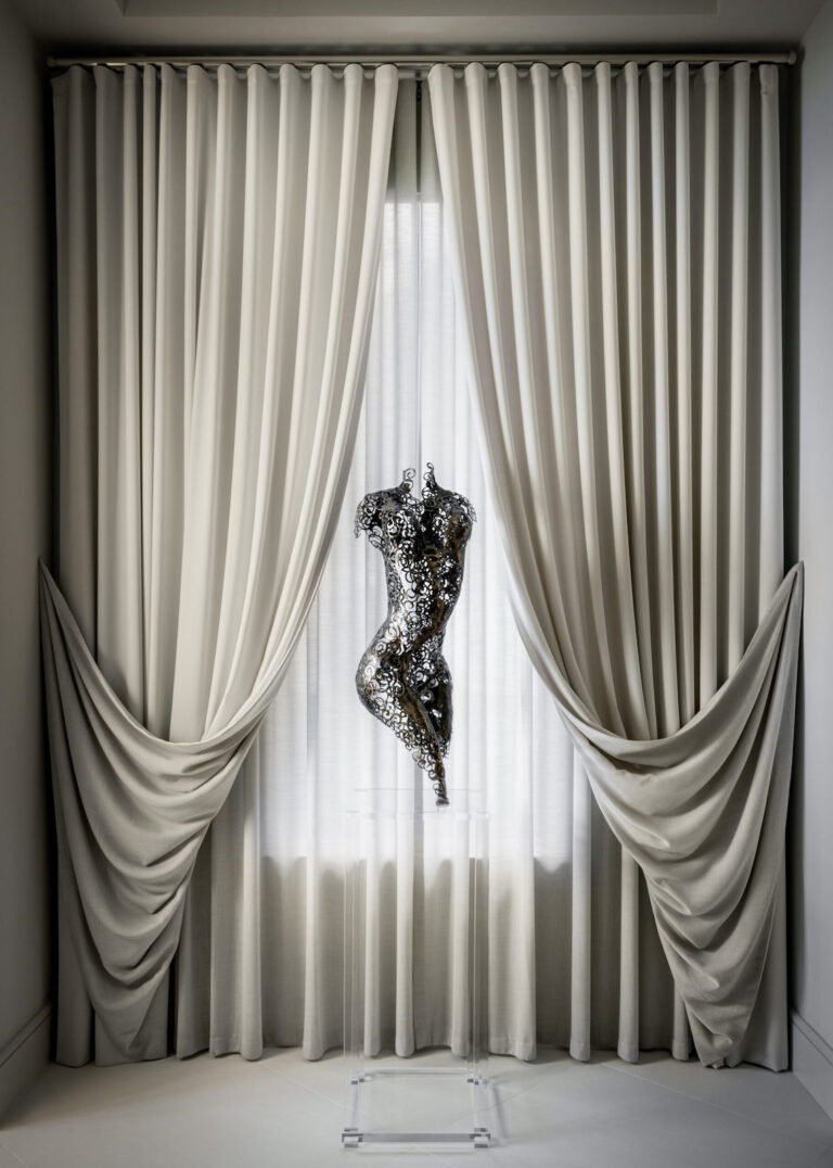 Modern hallway design with dramatic neutral drapery and a sculptural art piece, featured in the Modern Serenity project in Palm Beach.