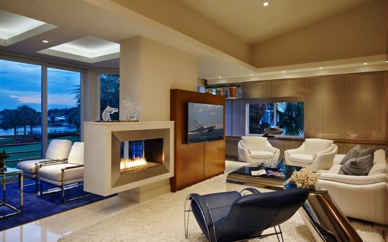 Warm modern living room with floating fireplace, cream leather chairs, and navy accents in Jupiter.