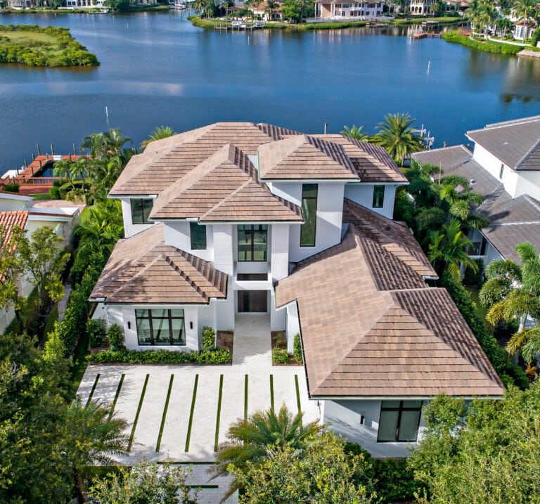Modern waterfront home with contemporary architecture, brown tile roof, and lake views in Palm Beach, Florida.